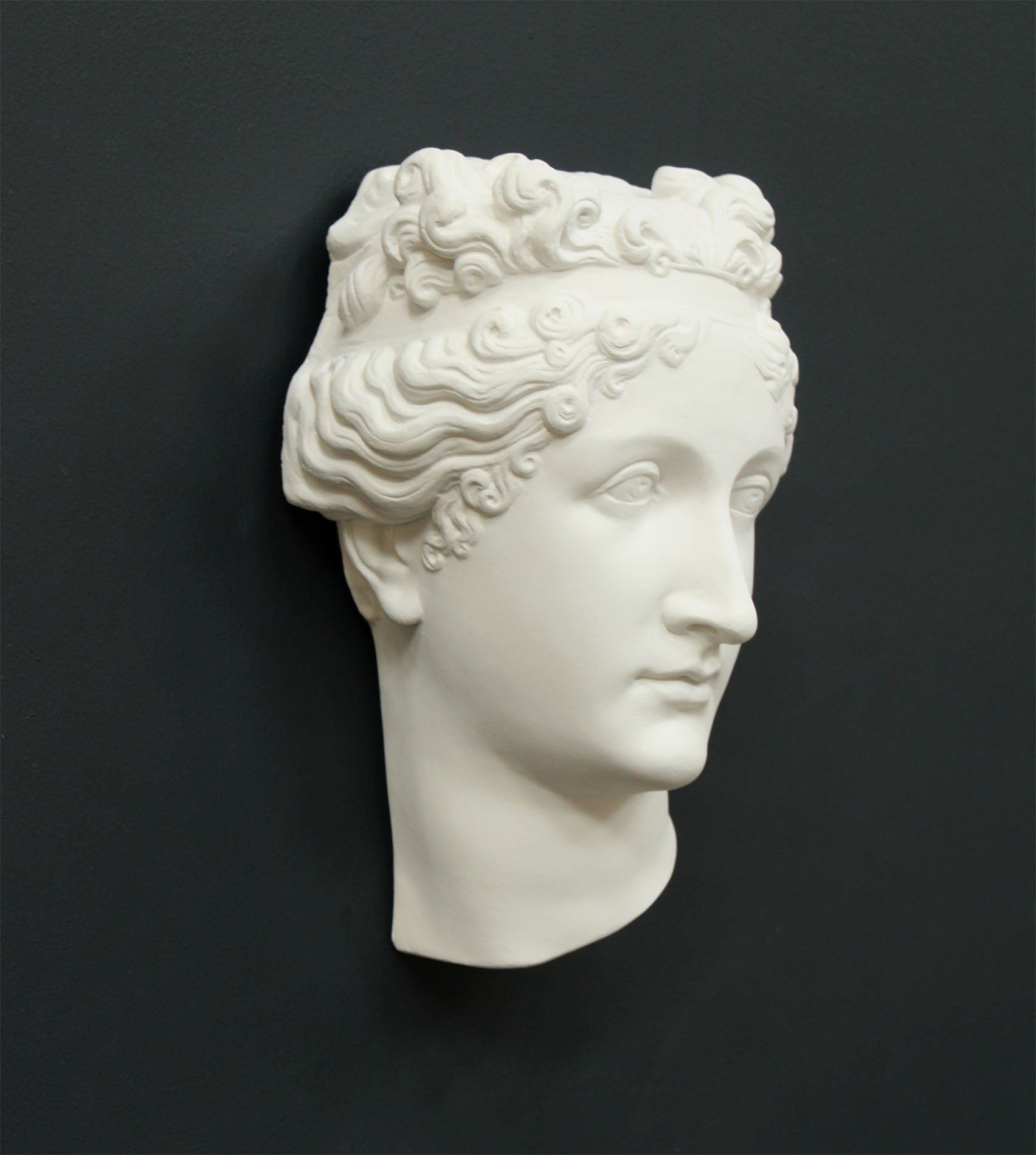 Photo of white plaster cast sculpture of mask/face of female with headband, namely Pauline Bonaparte, on gray background