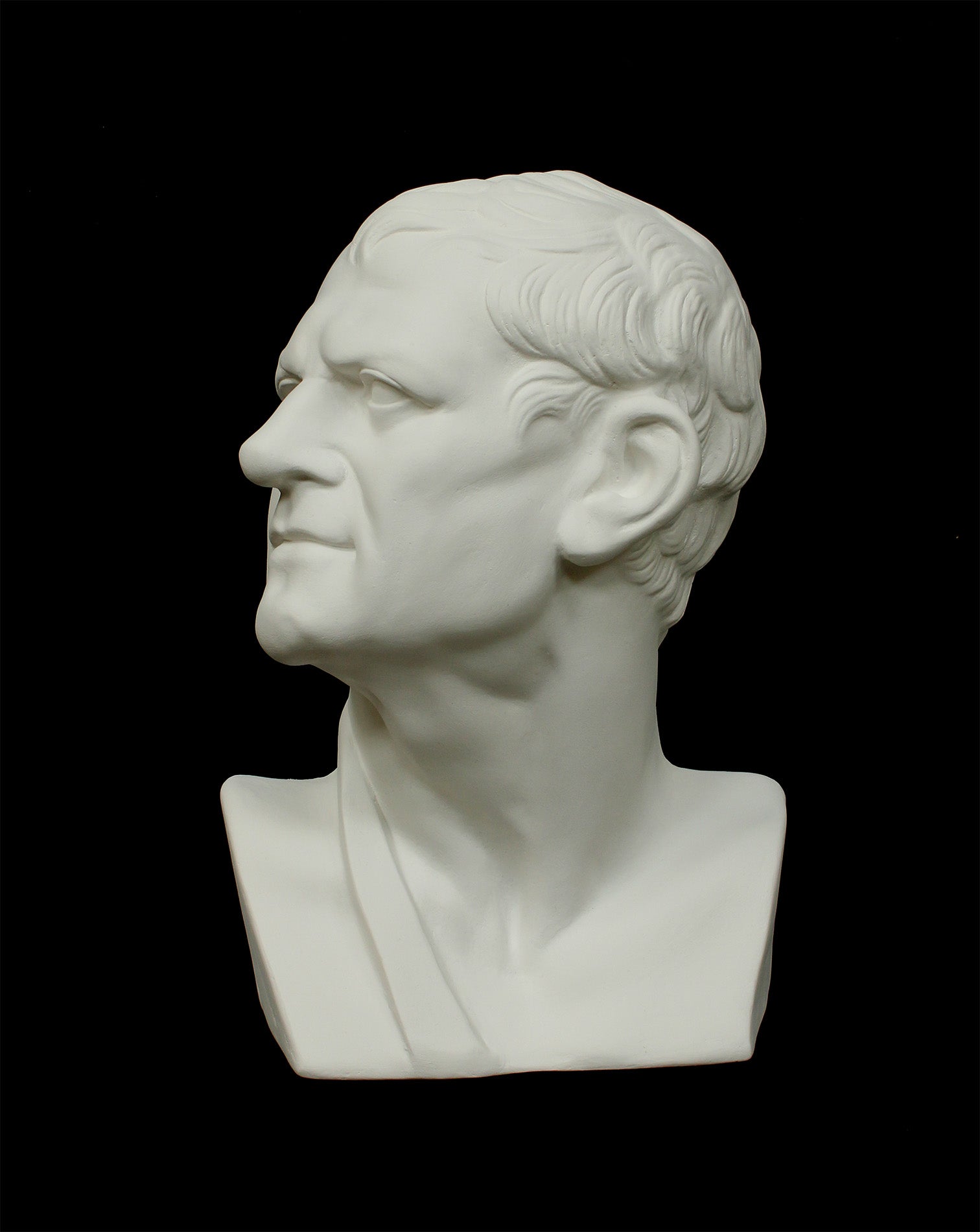 Photo of white plaster cast sculpture of mask/face of male facing right on black background