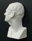 Photo of white plaster cast sculpture of mask/face of male facing right on gray background
