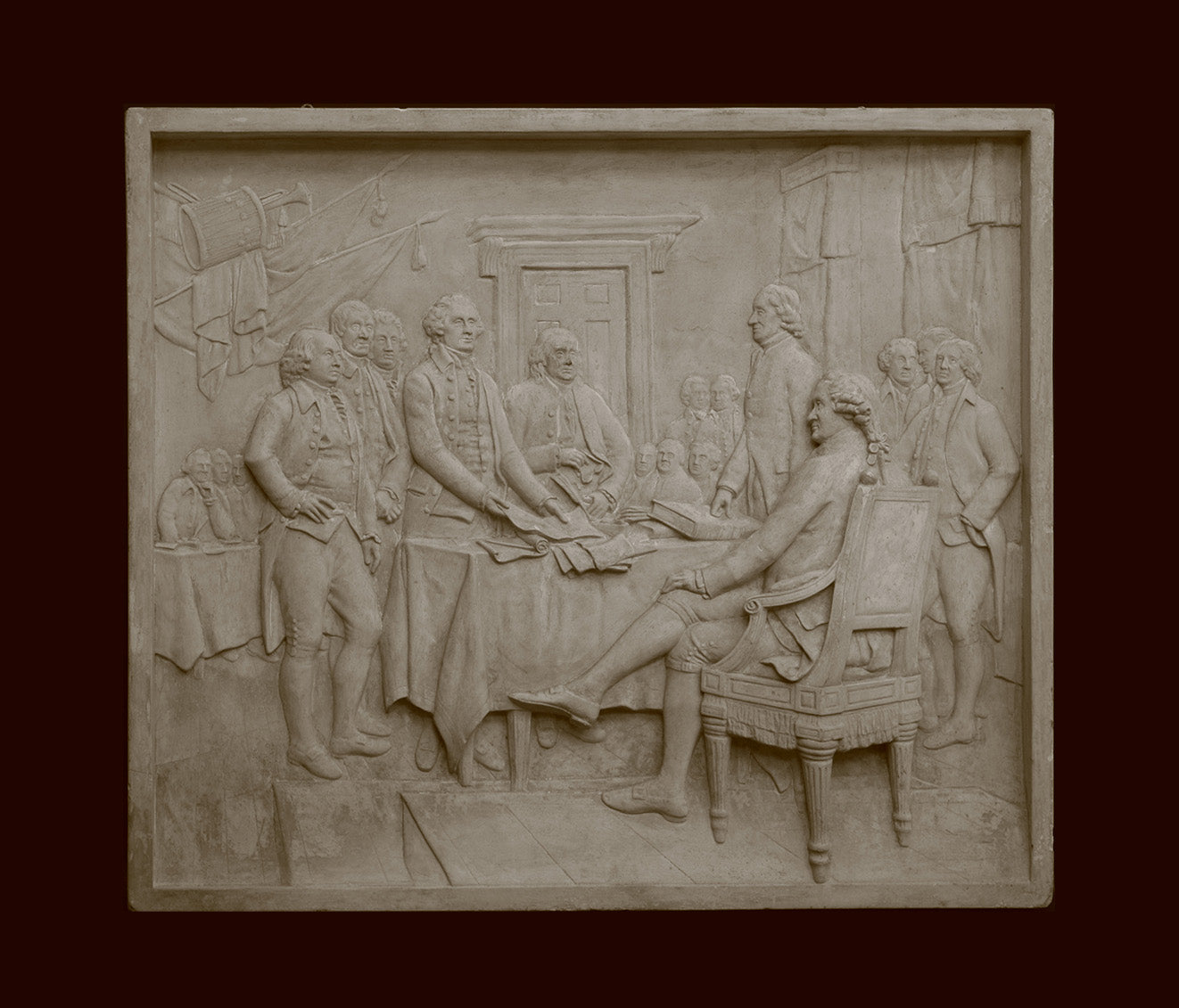 photo of off-white plaster cast relief sculpture of men around a table aka signing the Declaration of Independence, on black background