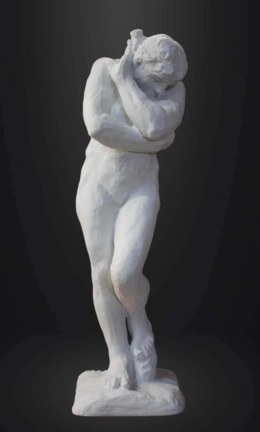 photo of white plaster cast sculpture of nude female figure hugging herself against gray background