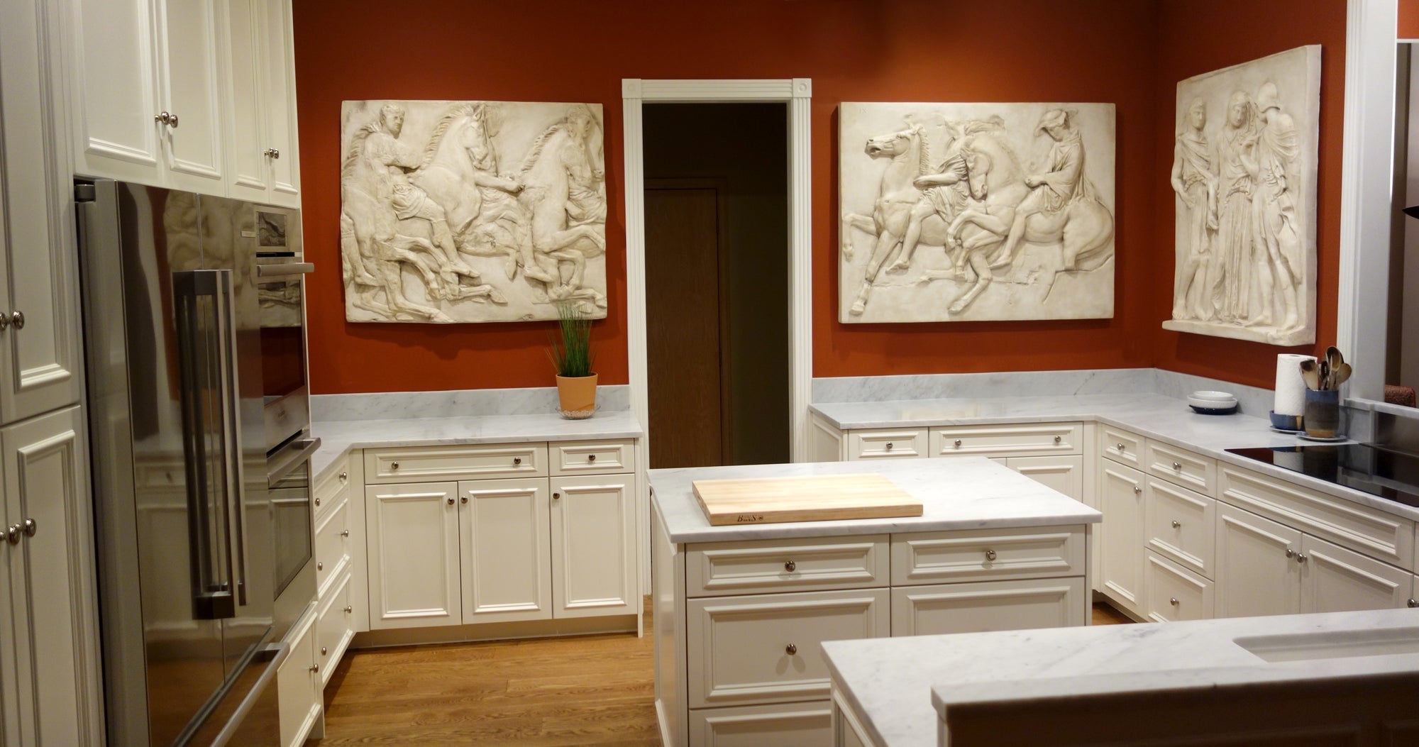 Modern kitchen with white cabinets, marble countertops, and decorative wall art.