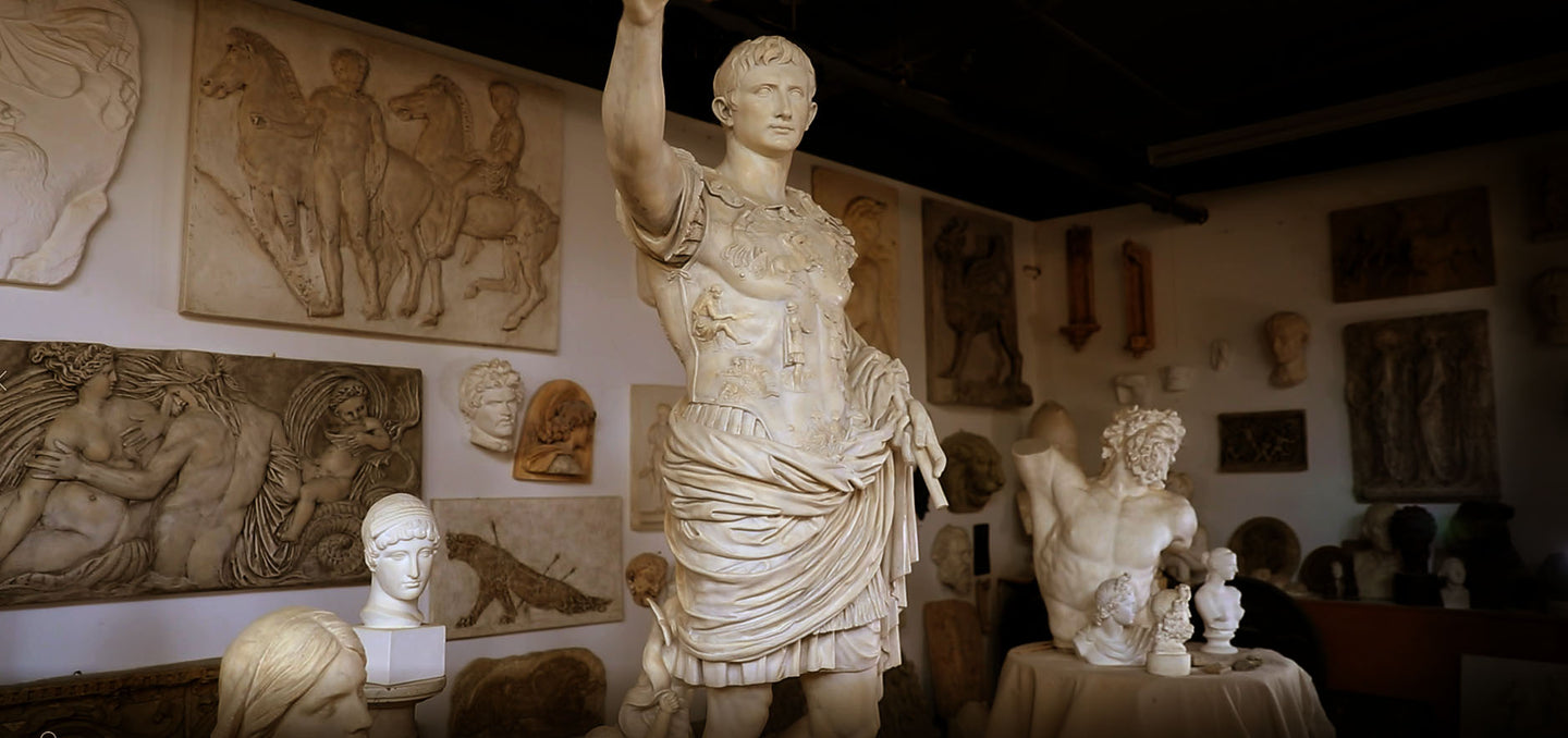 photo with sunset lighting of cast gallery with statues and busts in foreground on floor and pedestals and reliefs, masks, and ornamental items on walls