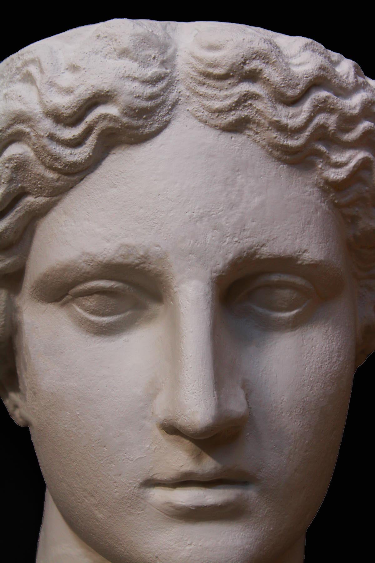 image of plaster cast sculpture mask of female, namely Athena, on a gray background