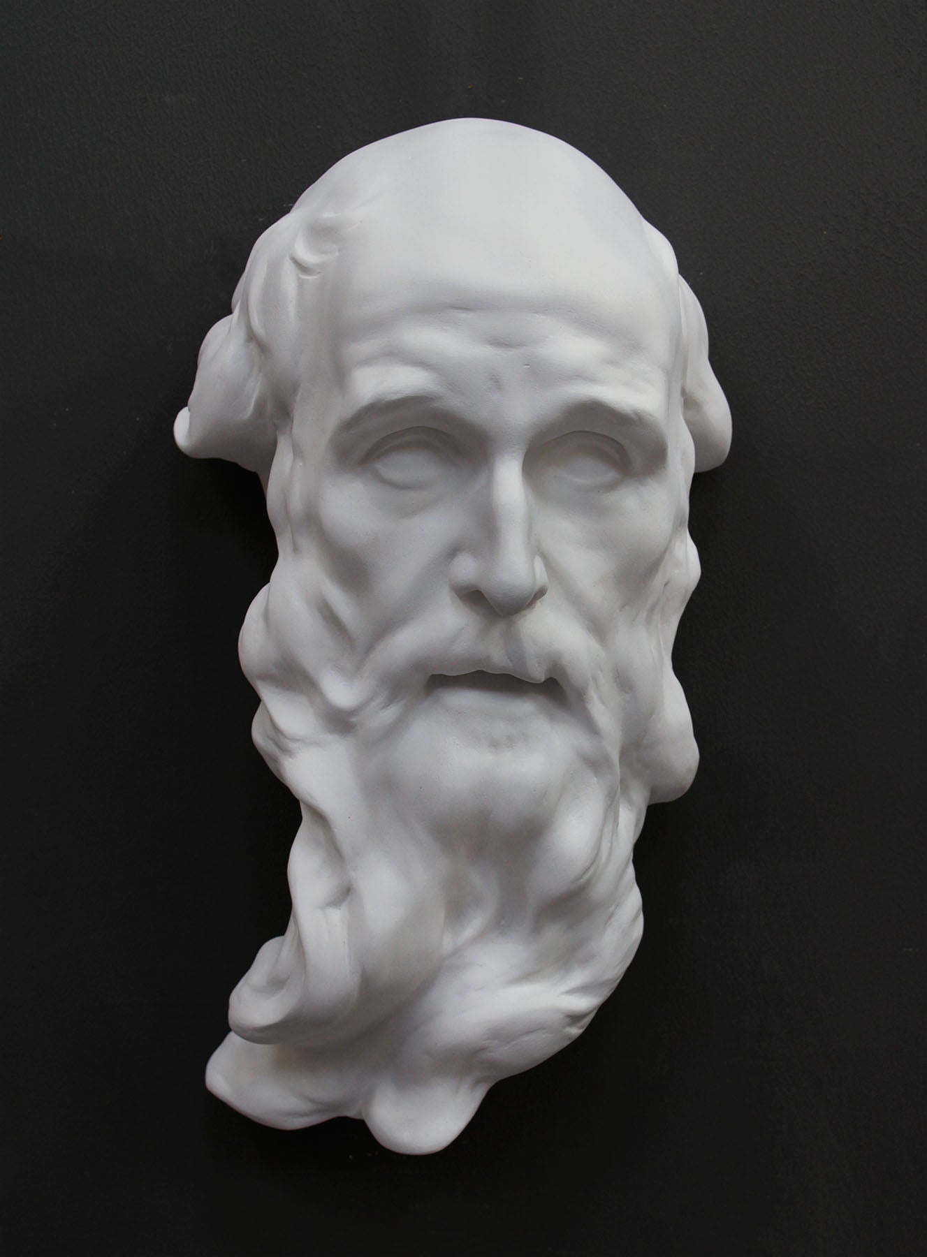 photo of plaster cast of the male face of Saint Andrew with long beard on gray background