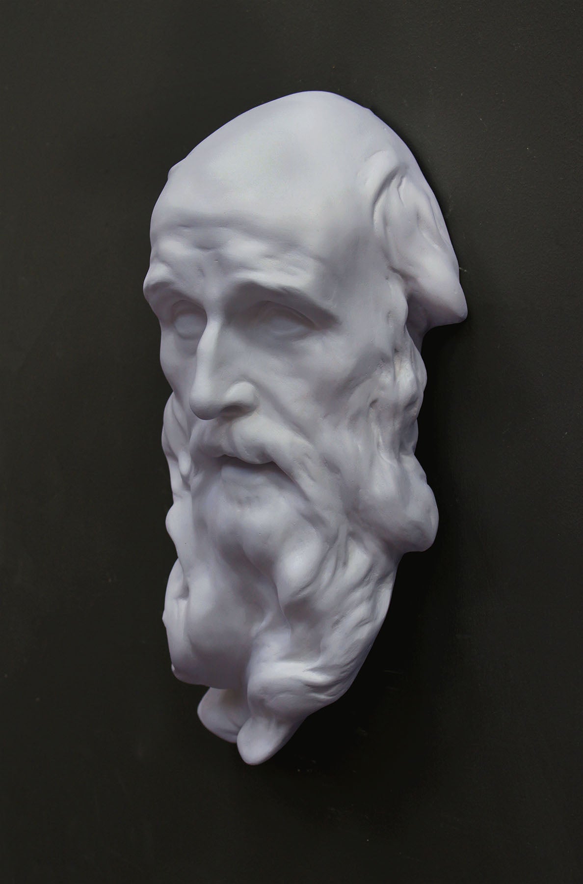 photo of plaster cast of the male face of Saint Andrew with long beard on gray background