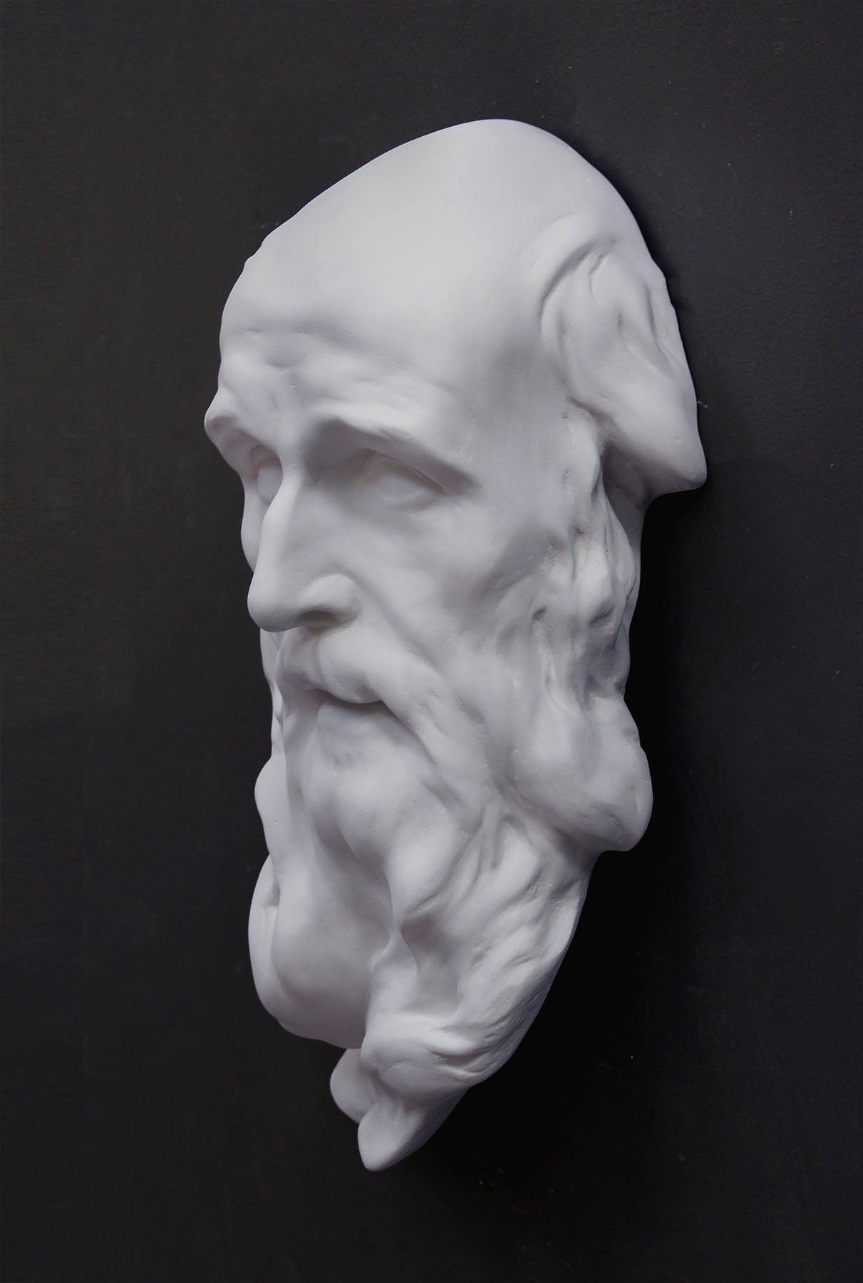 photo of plaster cast of the male face of Saint Andrew with long beard on gray background