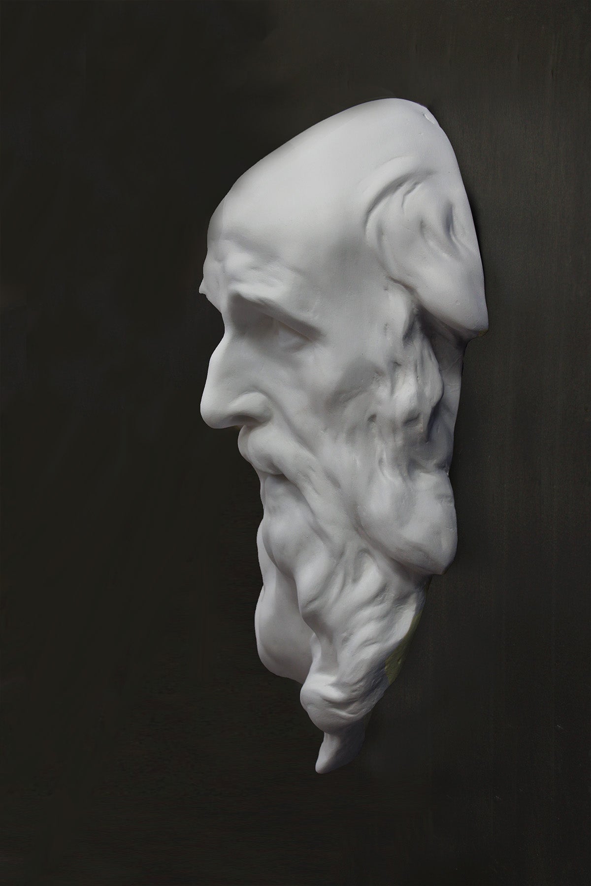photo of plaster cast of the male face of Saint Andrew with long beard on gray background