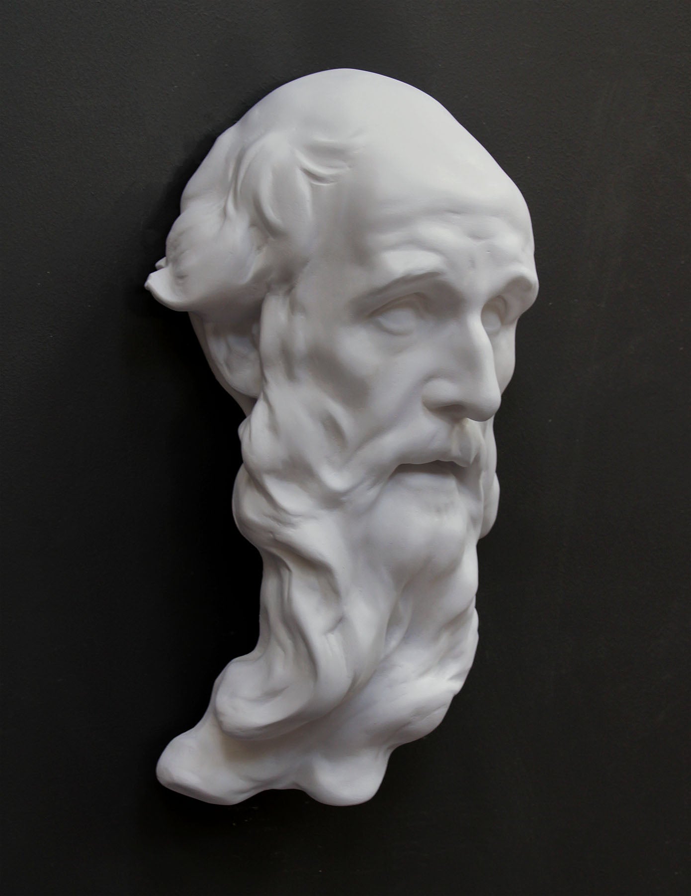 photo of plaster cast of the male face of Saint Andrew with long beard on gray background