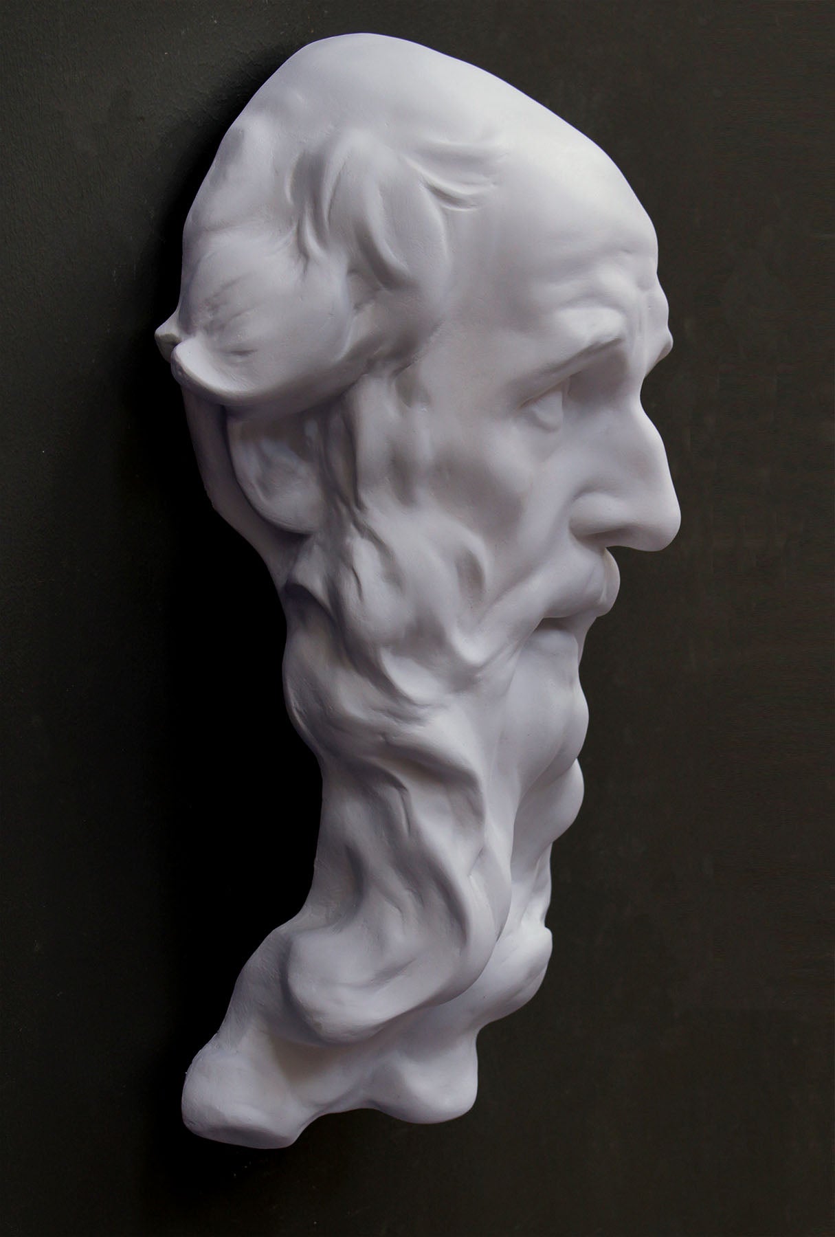 photo of plaster cast of the male face of Saint Andrew with long beard on gray background