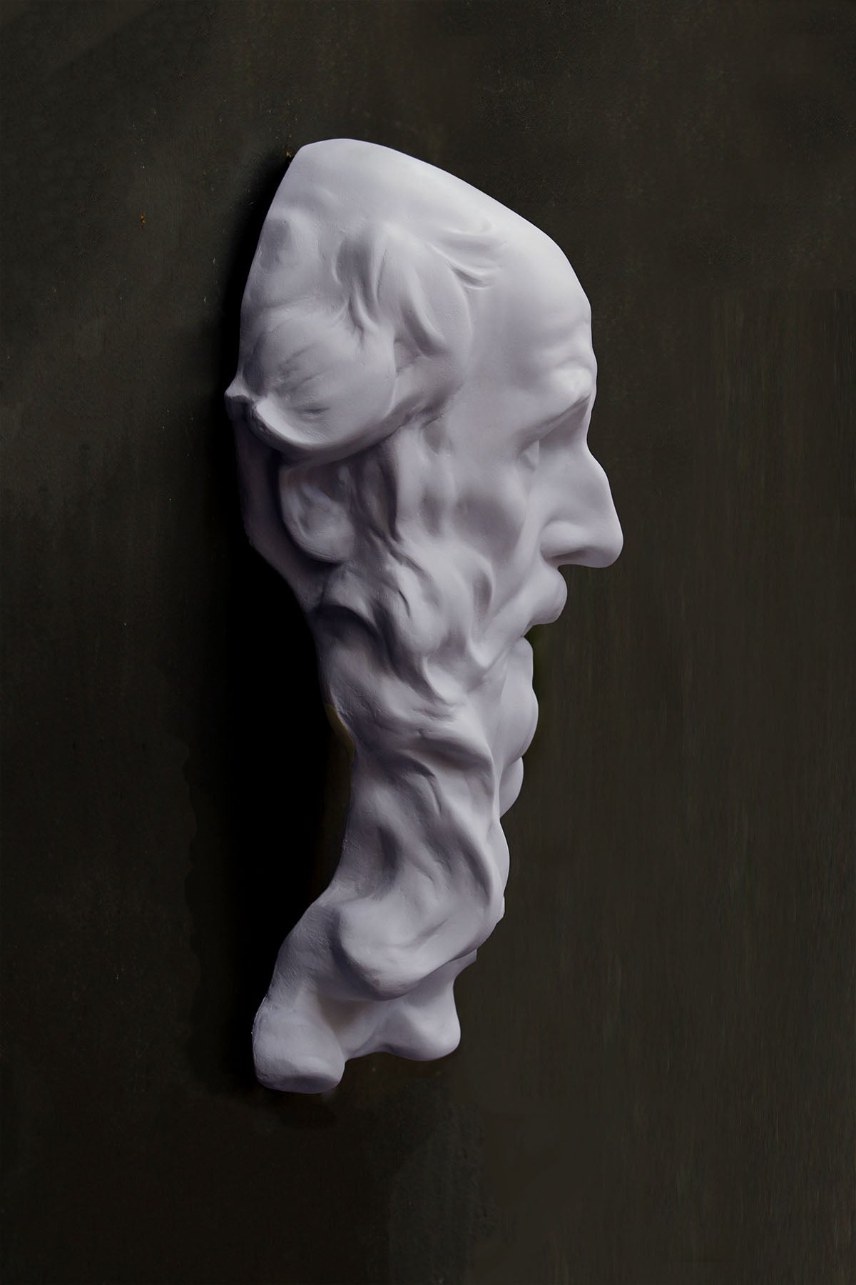 photo of plaster cast of the male face of Saint Andrew with long beard on gray background