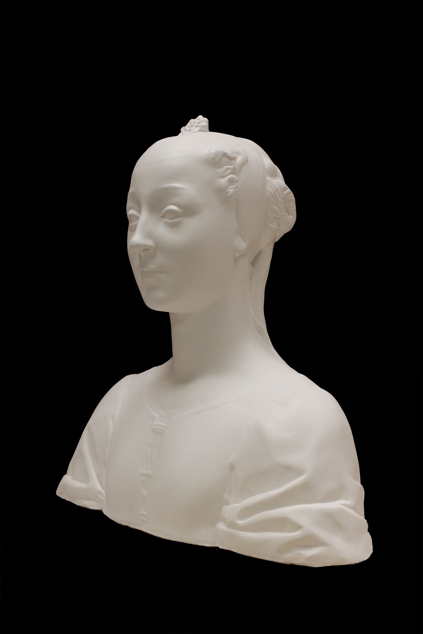 photo of white plaster cast of female bust with up-do and dress against black background