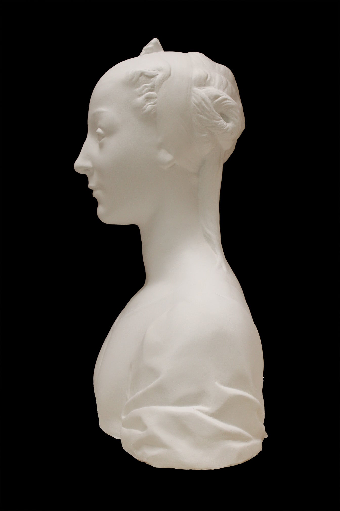 photo of white plaster cast of female bust with up-do and dress against black background