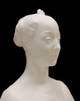 photo of white plaster cast of female bust with up-do and dress against black background