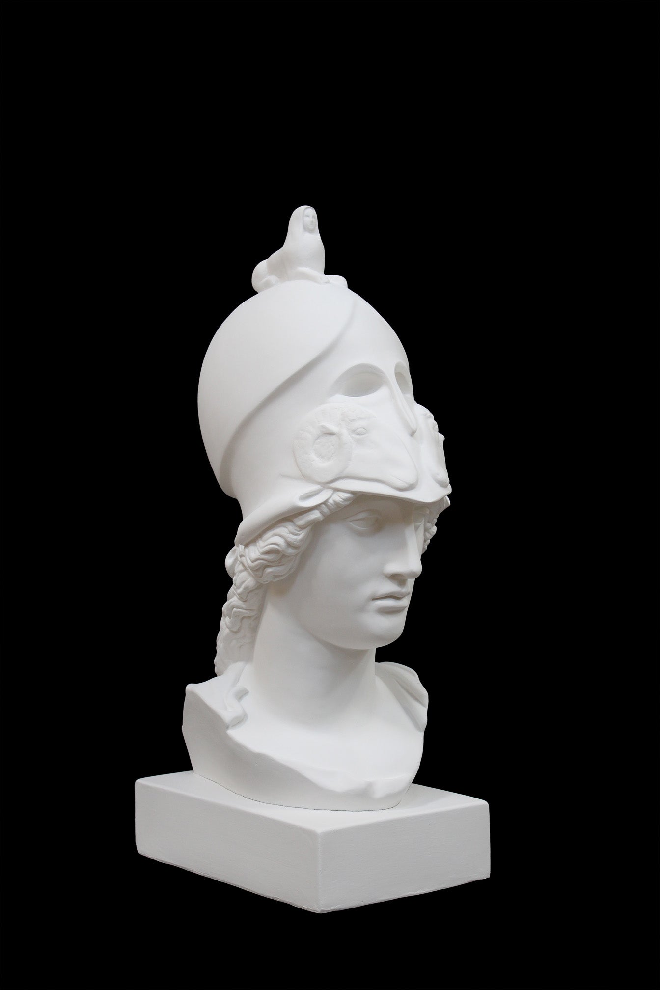 photo of plaster cast sculpture bust of female head, namely the goddess Athena, with a helmet on a black background