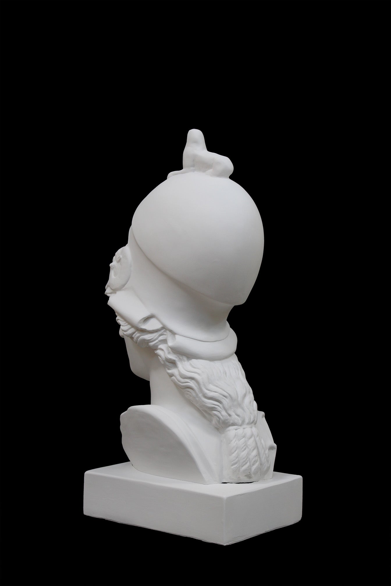 photo of plaster cast sculpture bust of female head, namely the goddess Athena, with a helmet on a black background