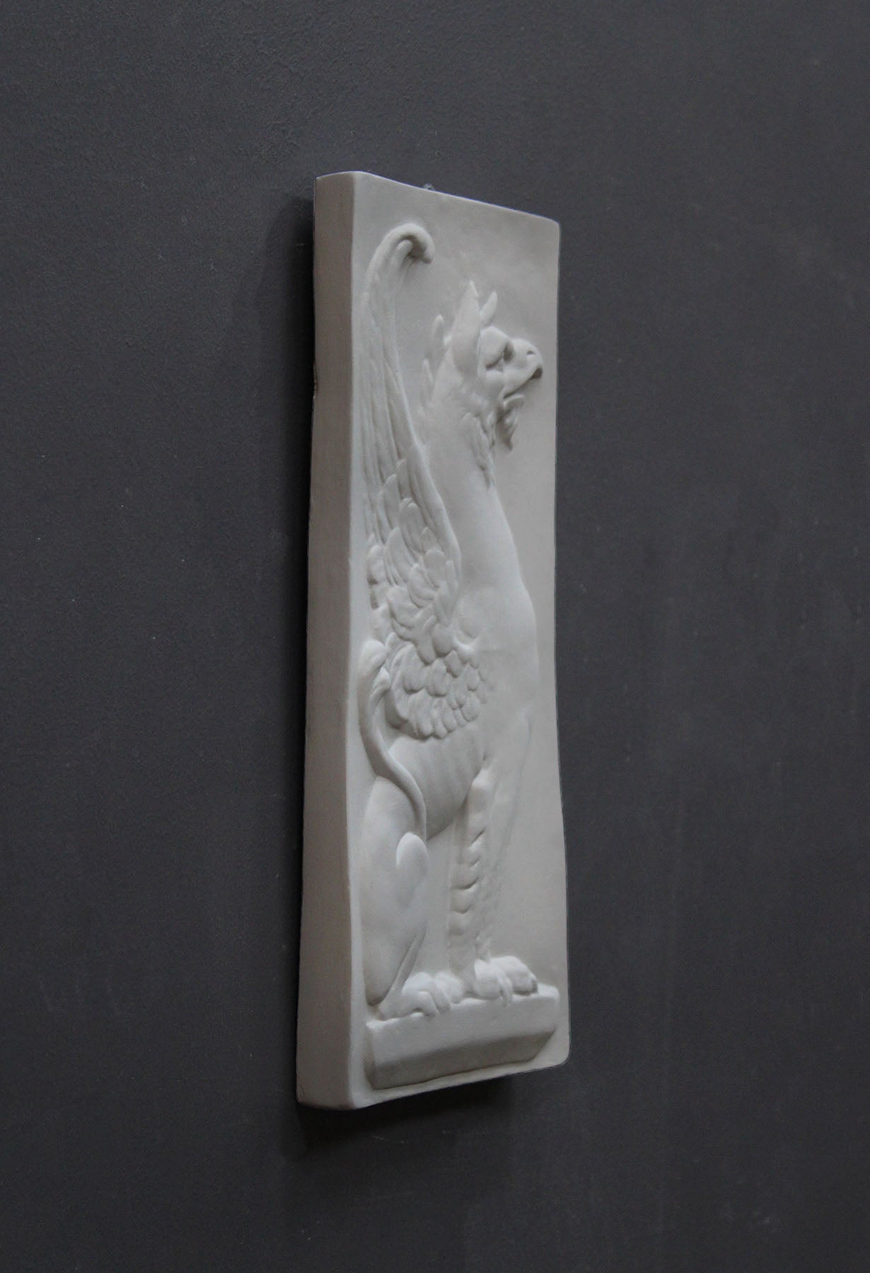 image of a plaster statue of a bust of griffin on a gray background