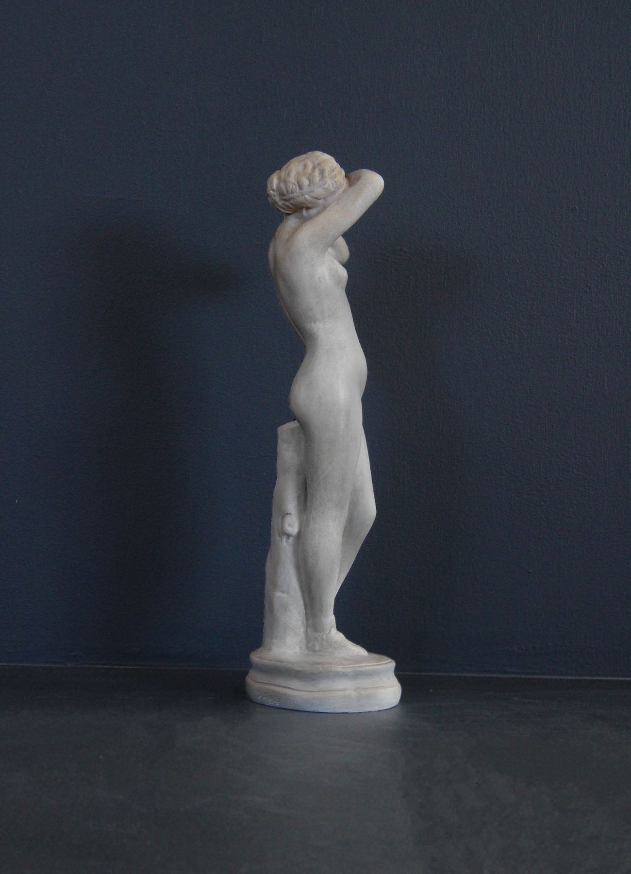 image of a plaster statue of a nude female figure, namely Phryne, on a gray background