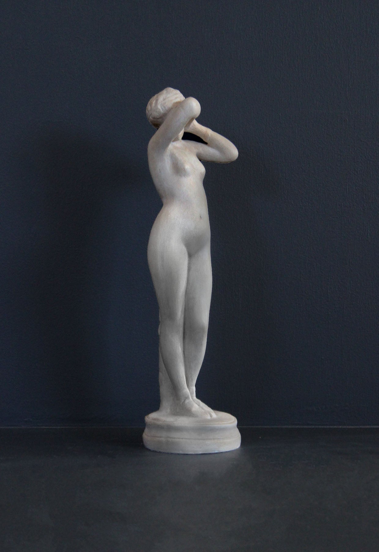 image of a plaster statue of a nude female figure, namely Phryne, on a gray background