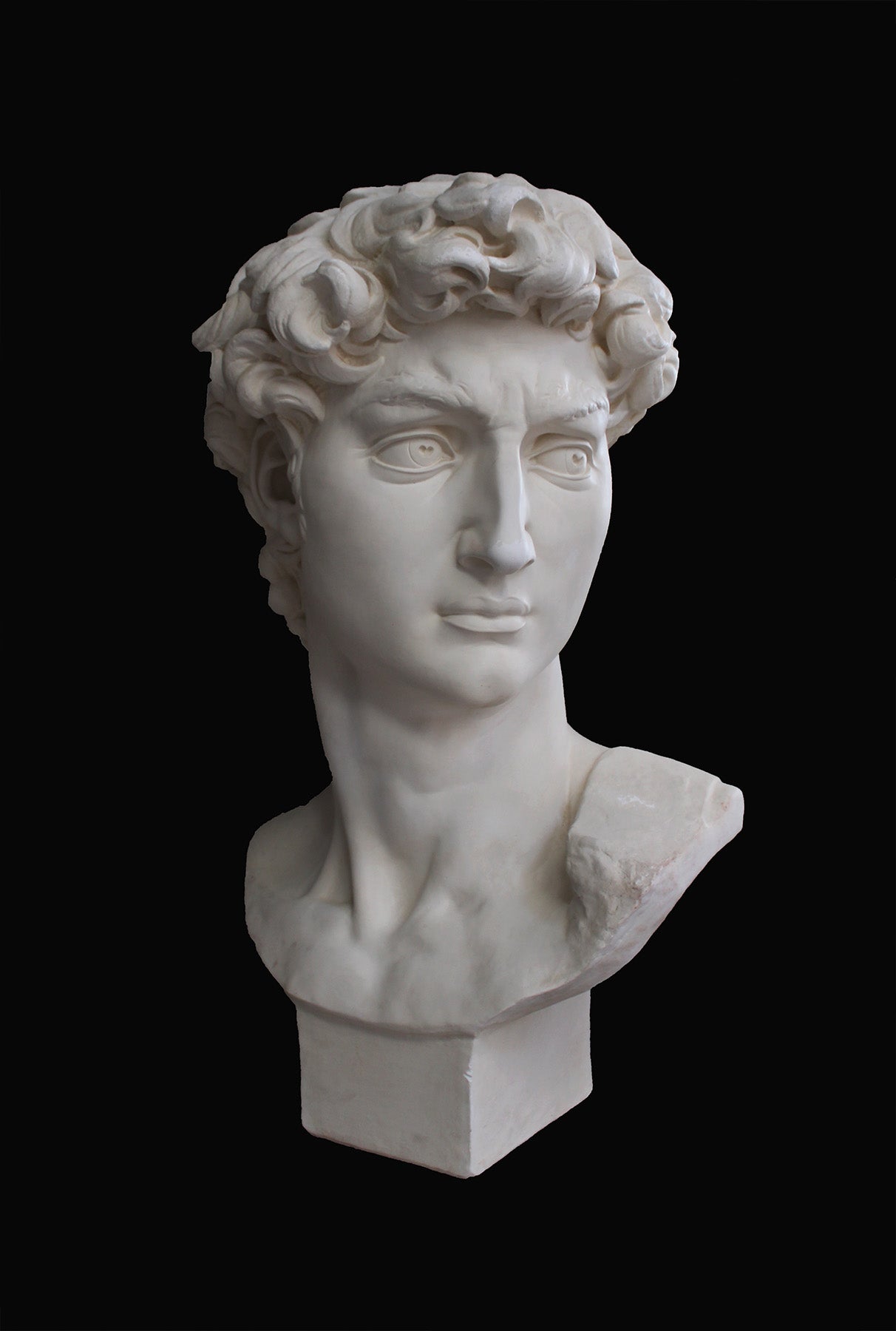 image of a plaster statue of a bust of david on a black background