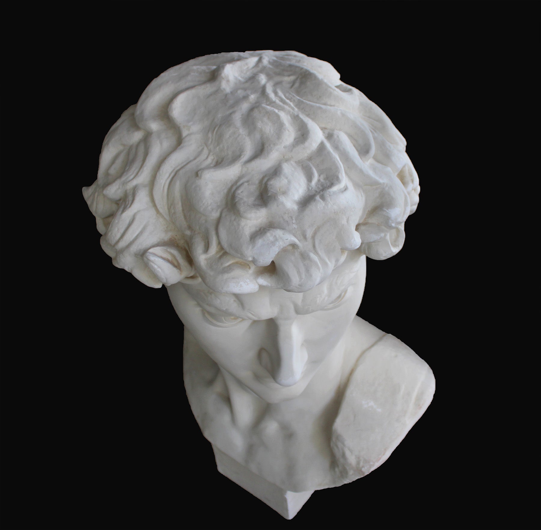 image of a plaster statue of a bust of david on a black background