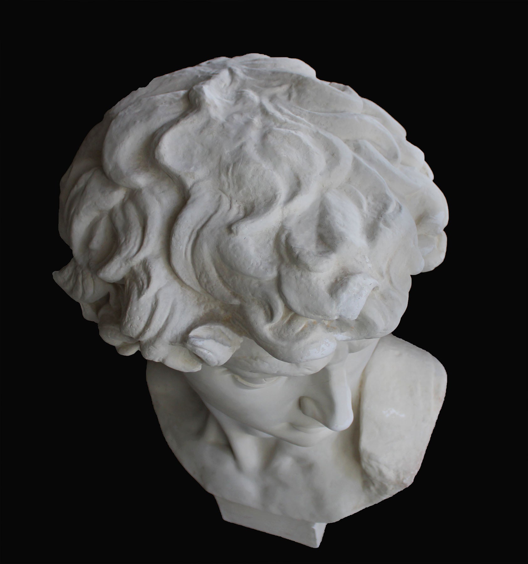 image of a plaster statue of a bust of david on a black background