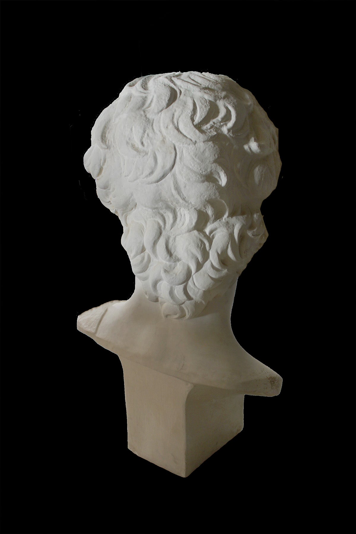image of a plaster statue of a bust of david on a black background
