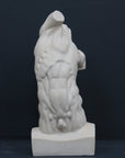 Photo of plaster cast sculpture of flayed male torso and a sculpting tool on a gray surface in front of a black background