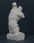 Photo of plaster cast sculpture of flayed male torso and a sculpting tool on a gray surface in front of a black background