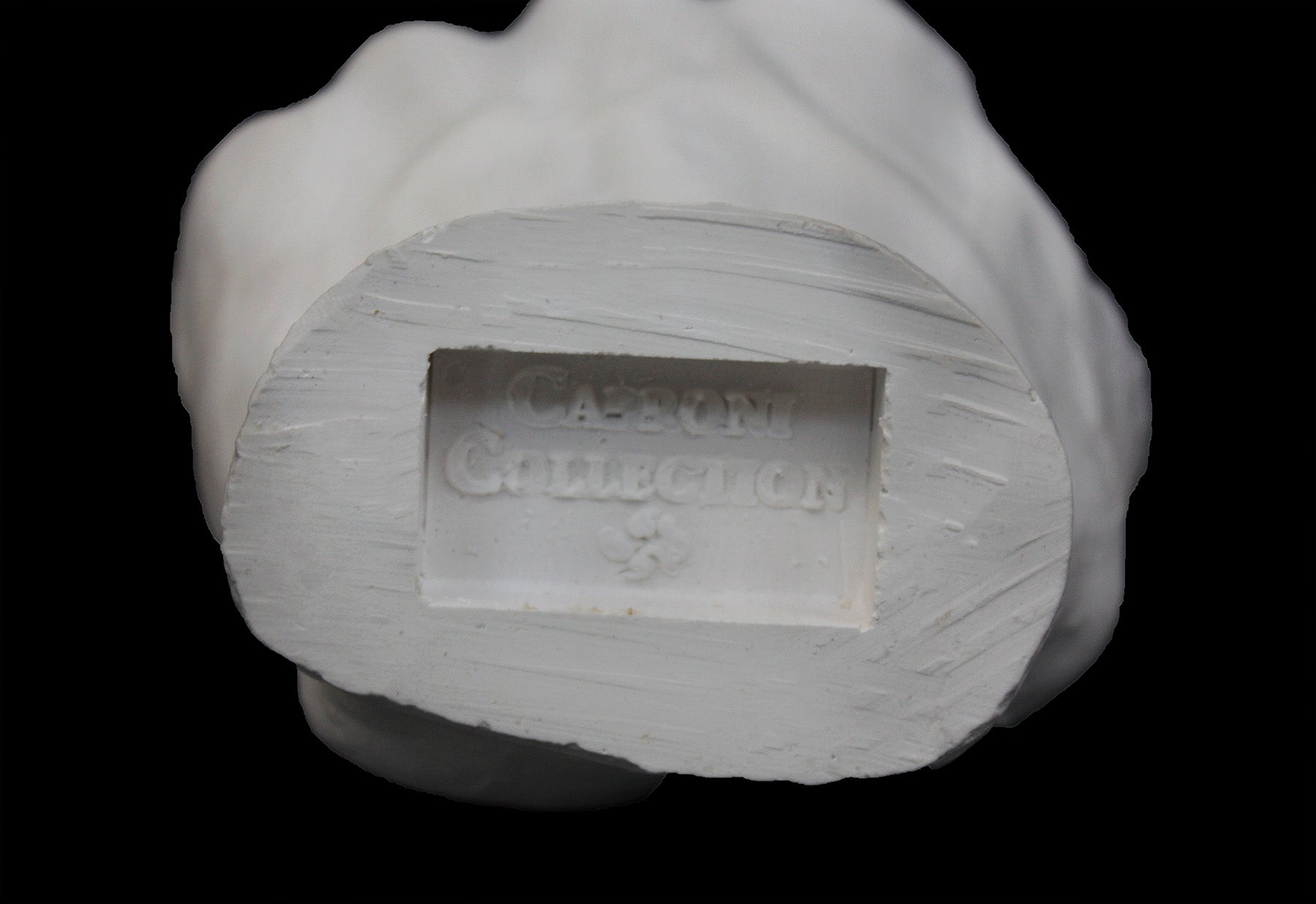 Photo of white plaster cast of a life cast of a clenched fisted hand on a black background, featuring the Caproni Collection stamp on the wrist