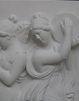 Photo with black background of plaster cast sculpture relief of females playing instruments