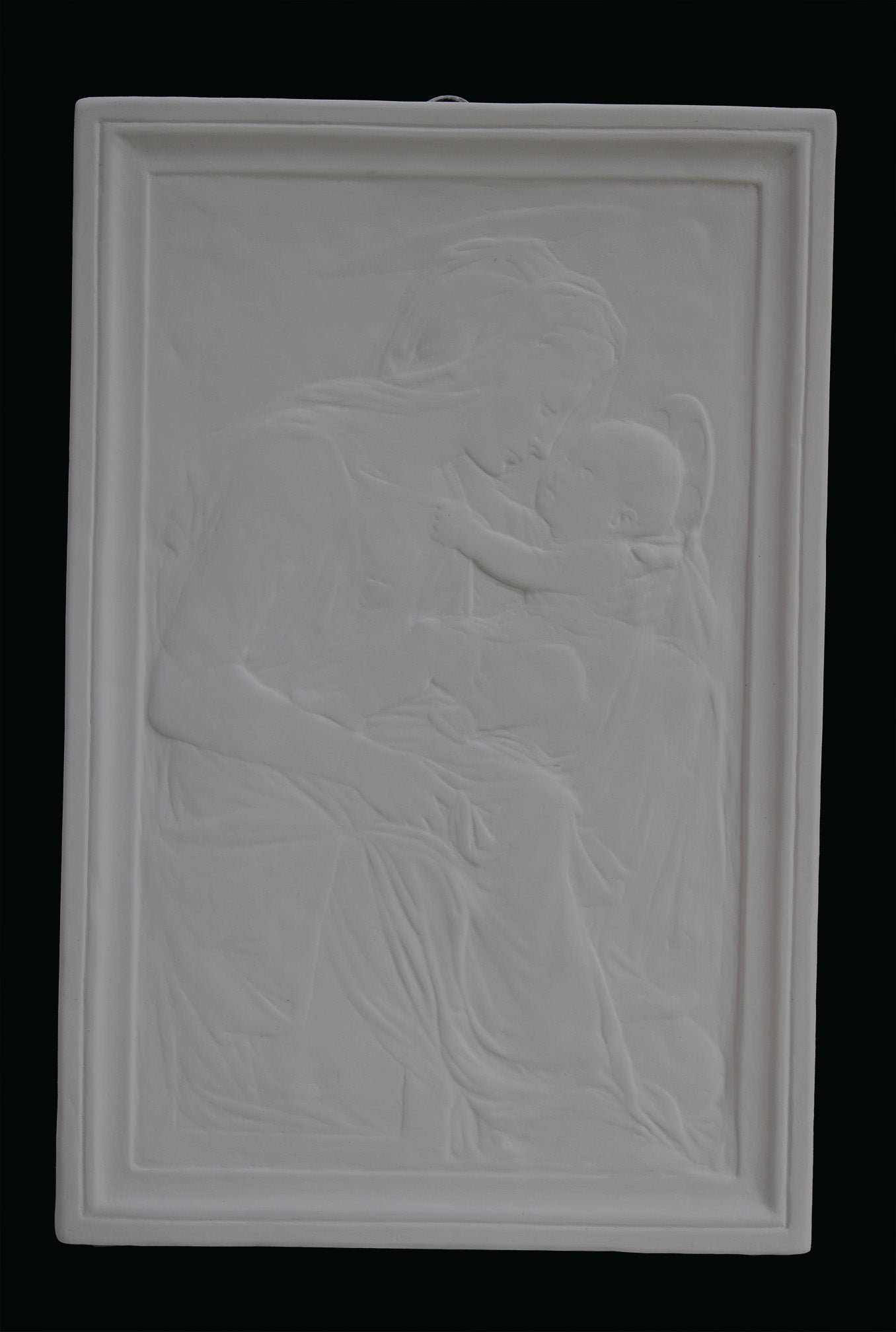 photo detail of plaster cast sculpture relief of the Madonna holding baby Jesus on her lap on black background