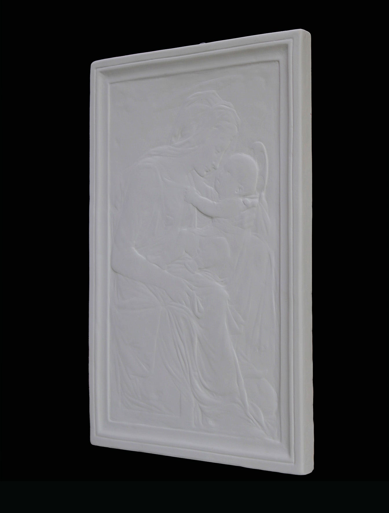 photo detail of plaster cast sculpture relief of the Madonna holding baby Jesus on her lap on black background