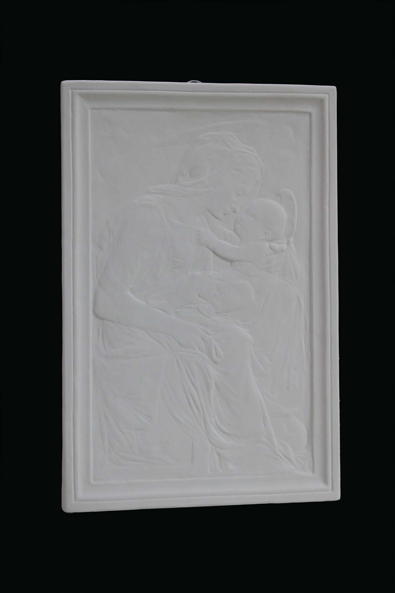 photo detail of plaster cast sculpture relief of the Madonna holding baby Jesus on her lap on black background