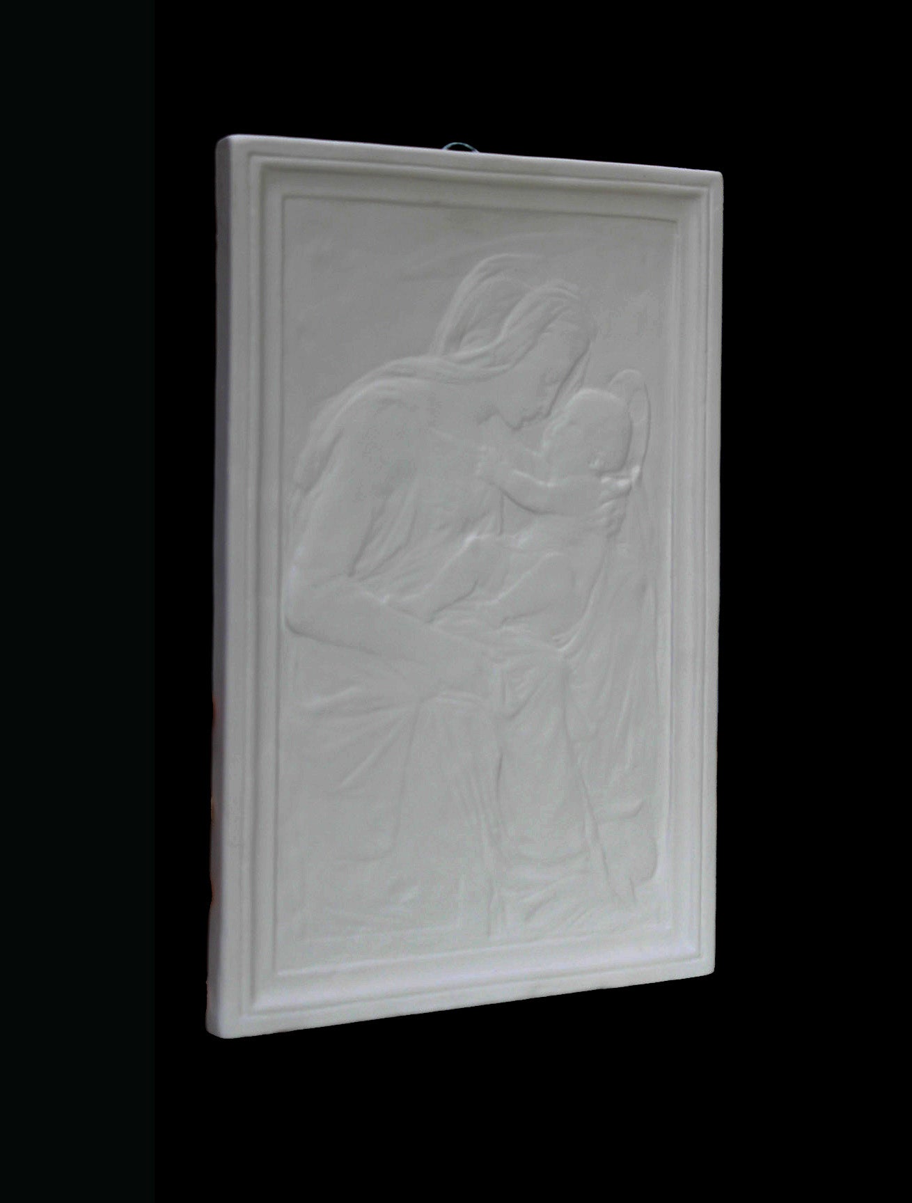 photo detail of plaster cast sculpture relief of the Madonna holding baby Jesus on her lap on black background