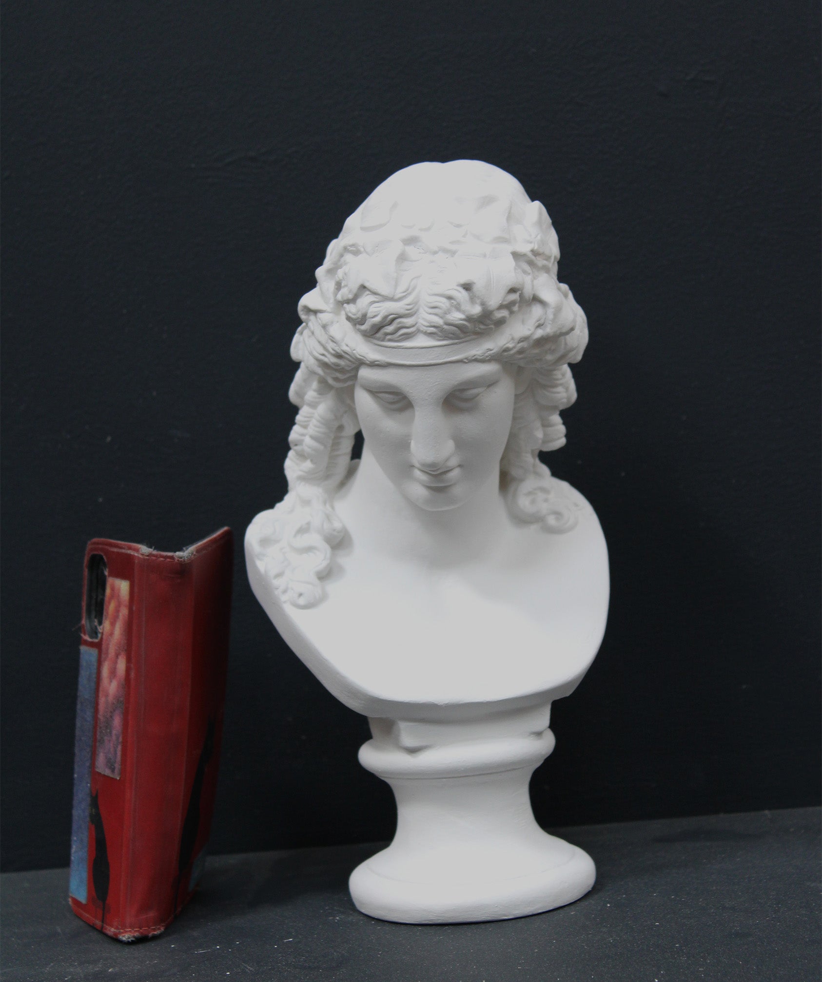 photo of plaster cast of sculpture bust of Ariadne or Bacchus with long, curly hair and head band on a black background