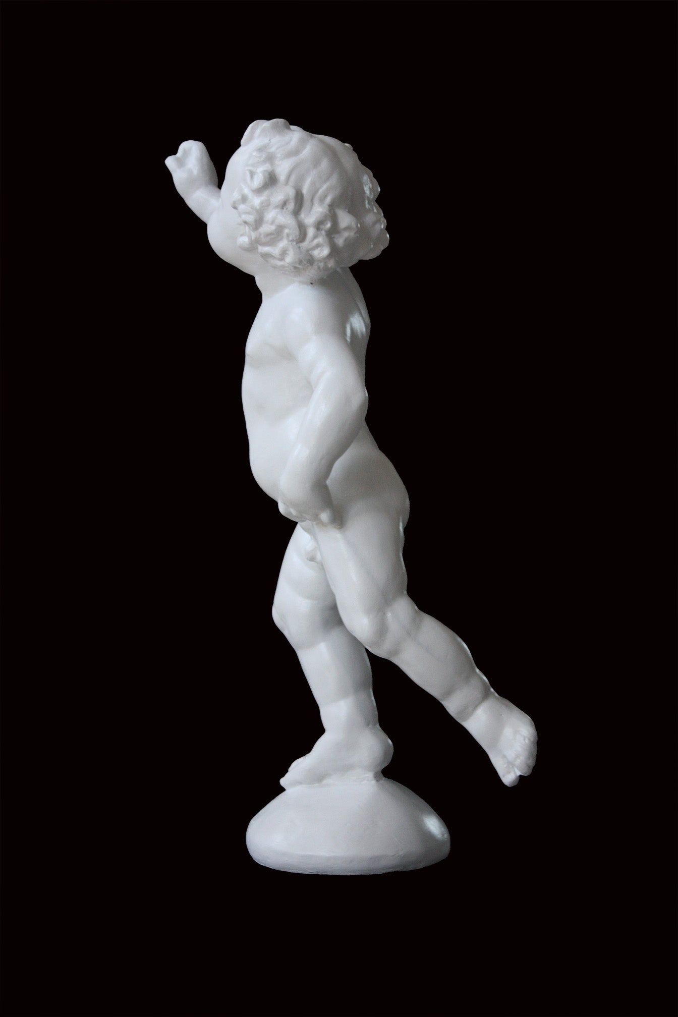 Photo of a sculpture of a cherub on a black background