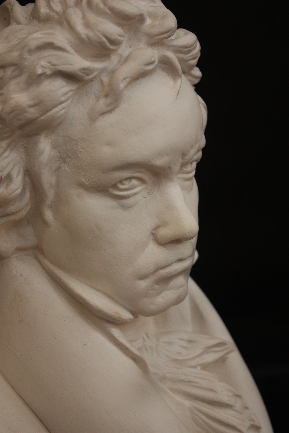 image of a plaster statue of a bust of Beethoven on a black background