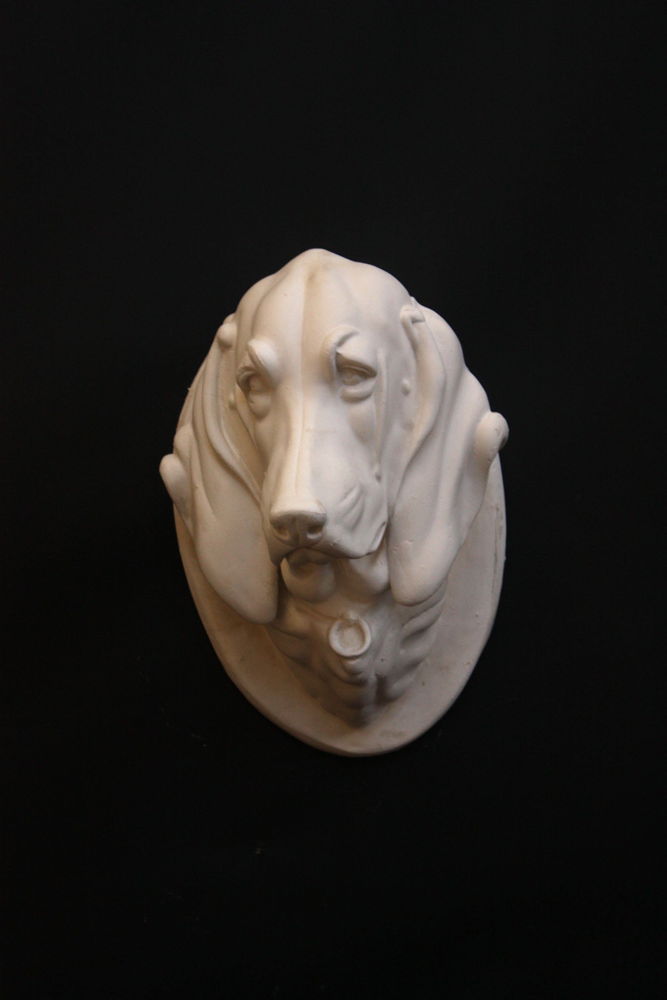 photo of a sculpture of a dog head on a black background 