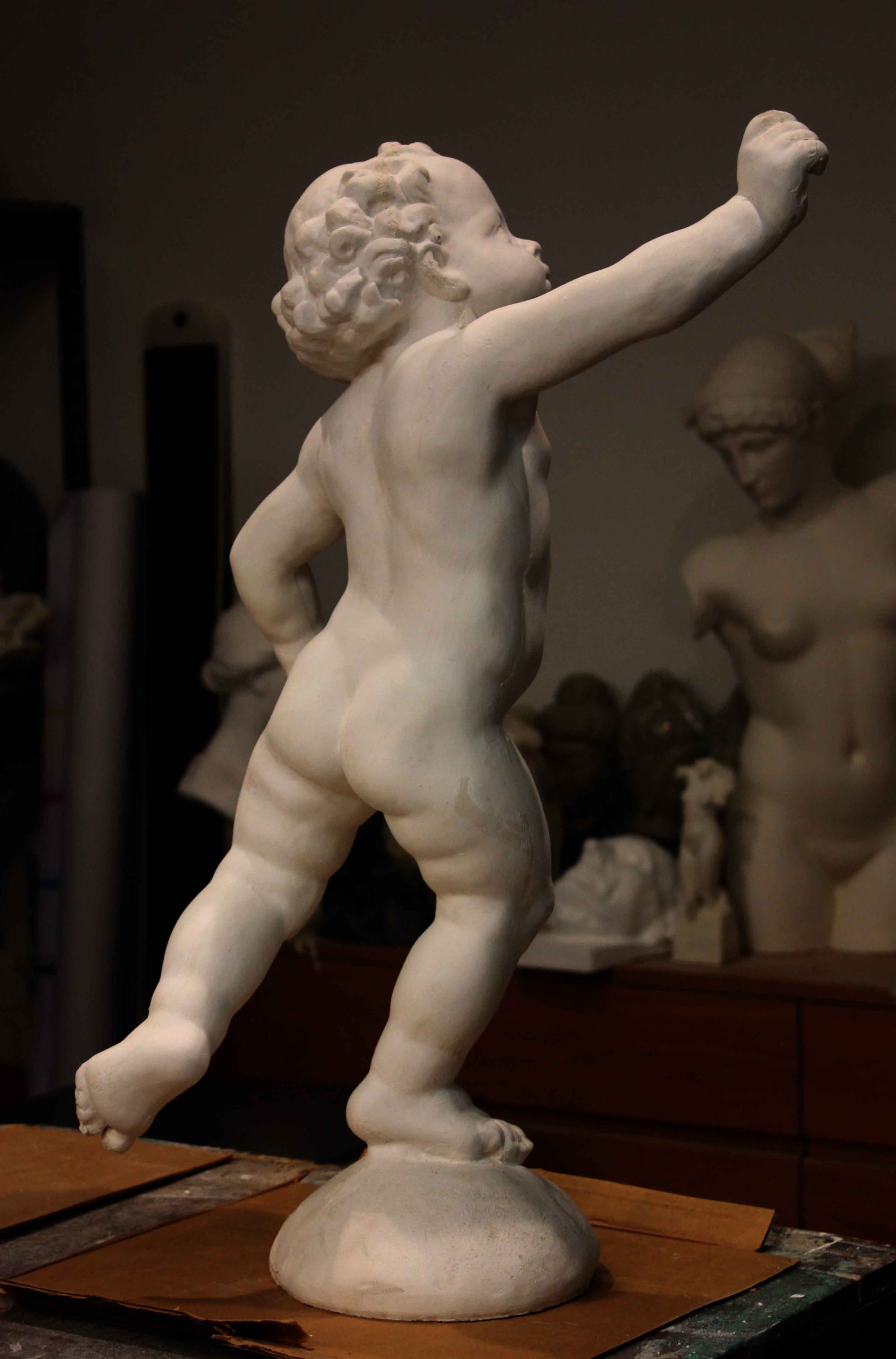 Photo of a sculpture of a cherub on a black background