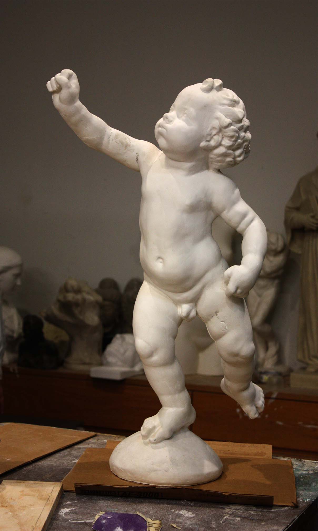 Photo of a sculpture of a cherub on a black background