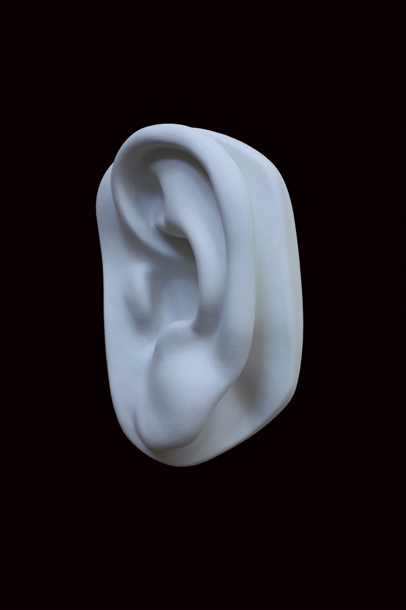 photo of cast sculpture drawing of left ear from Michelangelo's David statue against a black background