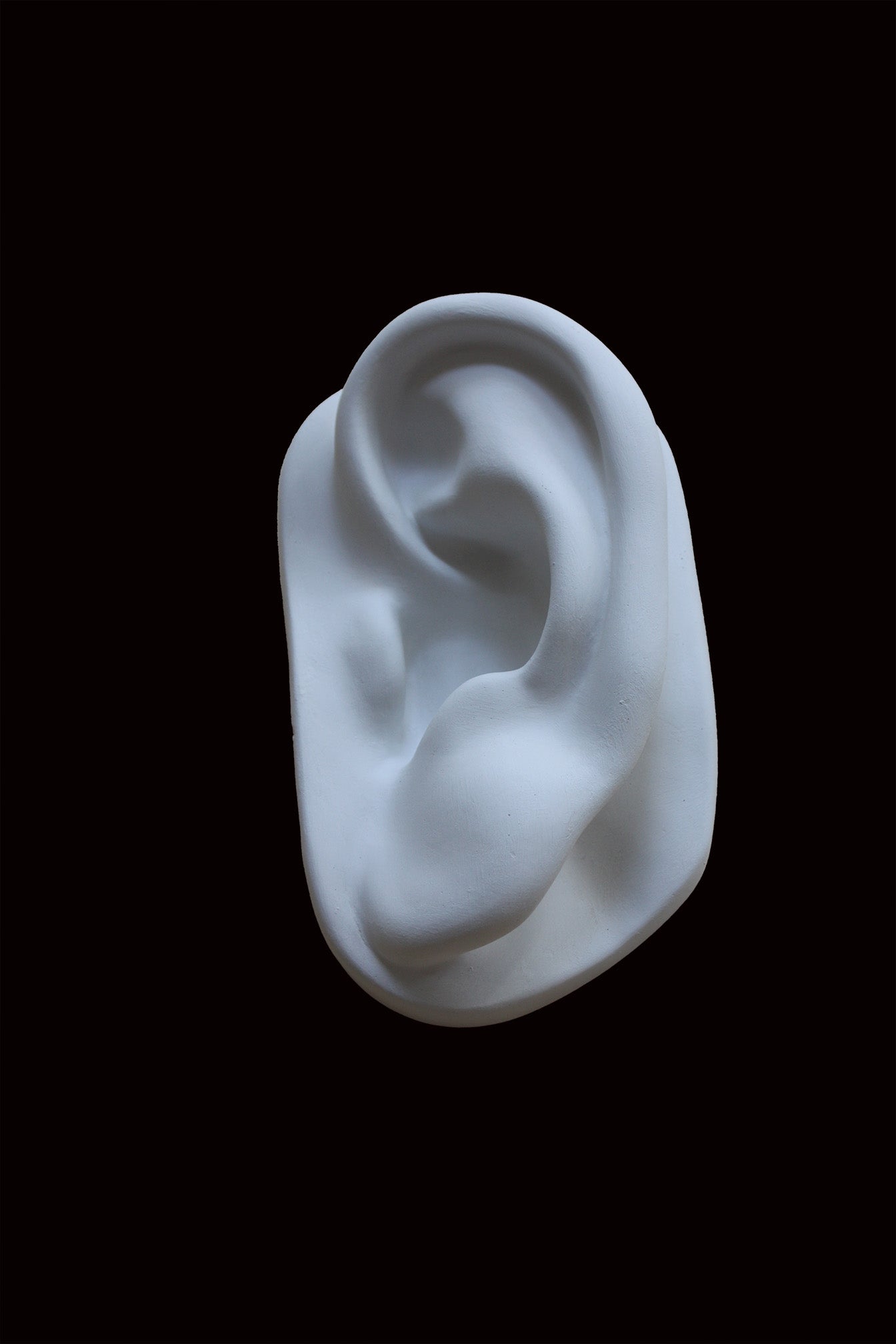 photo of cast sculpture drawing of left ear from Michelangelo's David statue against a black background