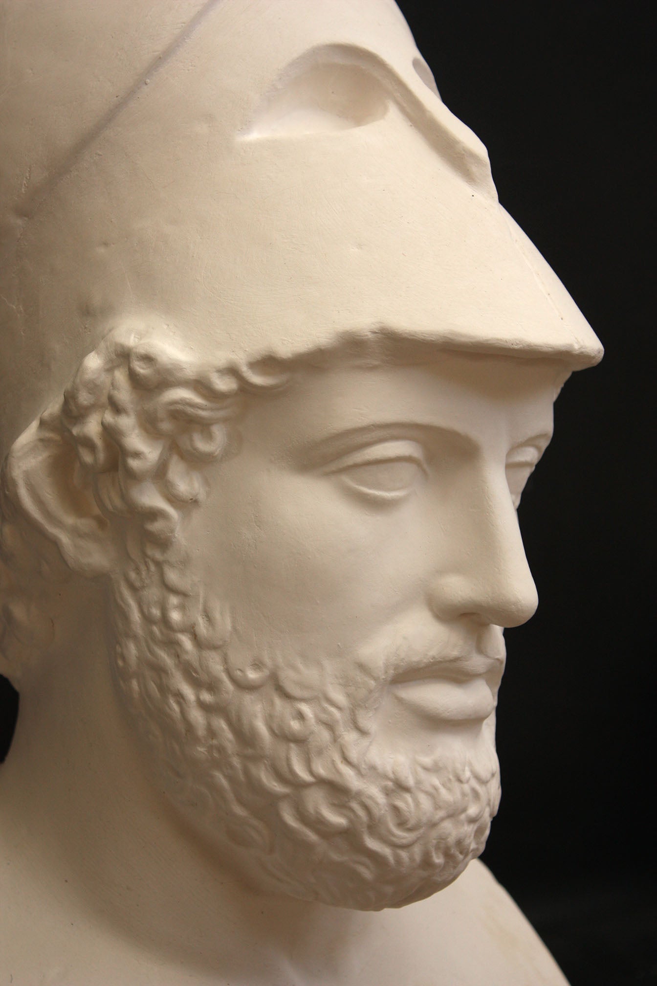 close-up photo of male sculpture with beard and helmet on a black background