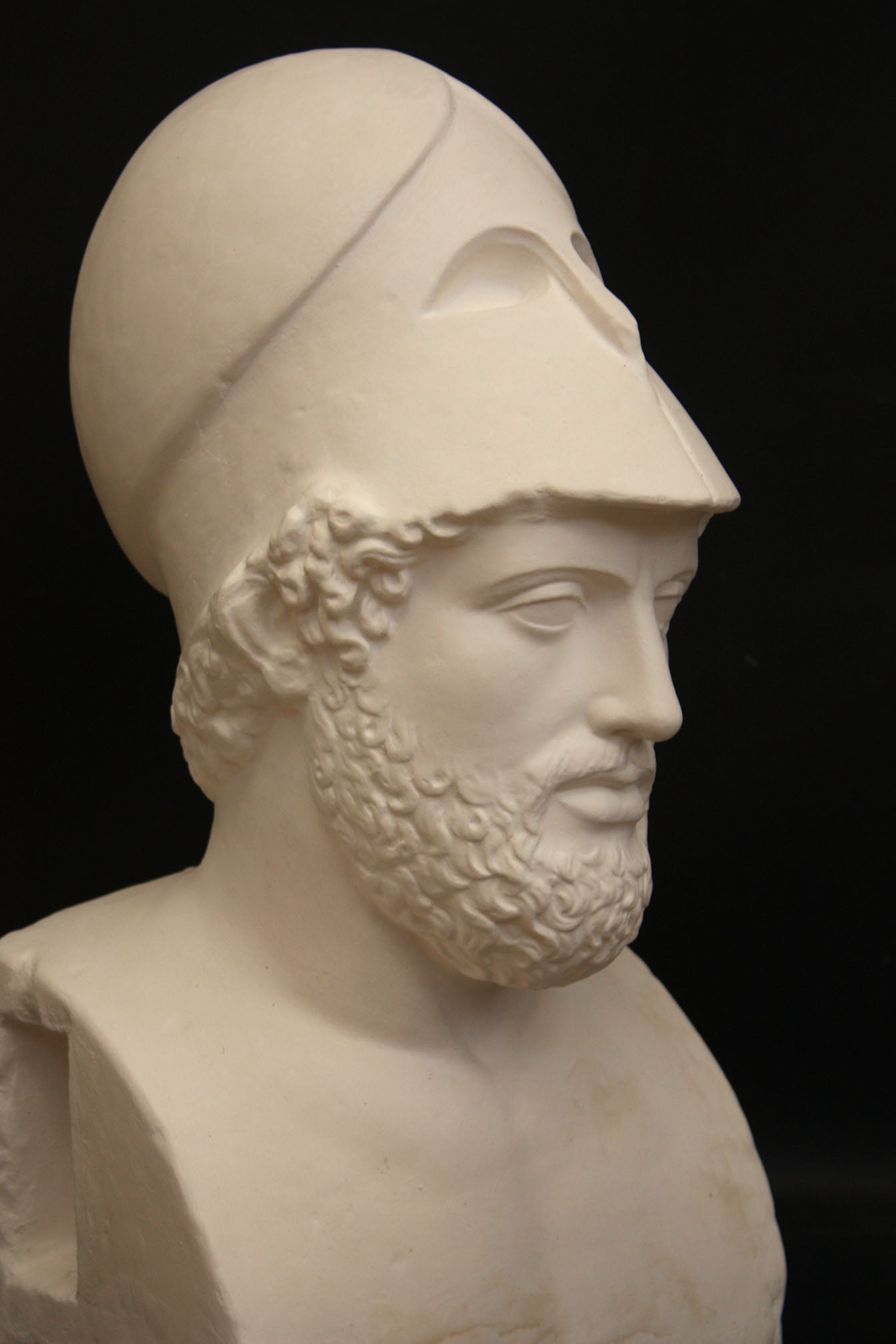 Photo of a sculpture of a man with a beard and a helmet, on a black background