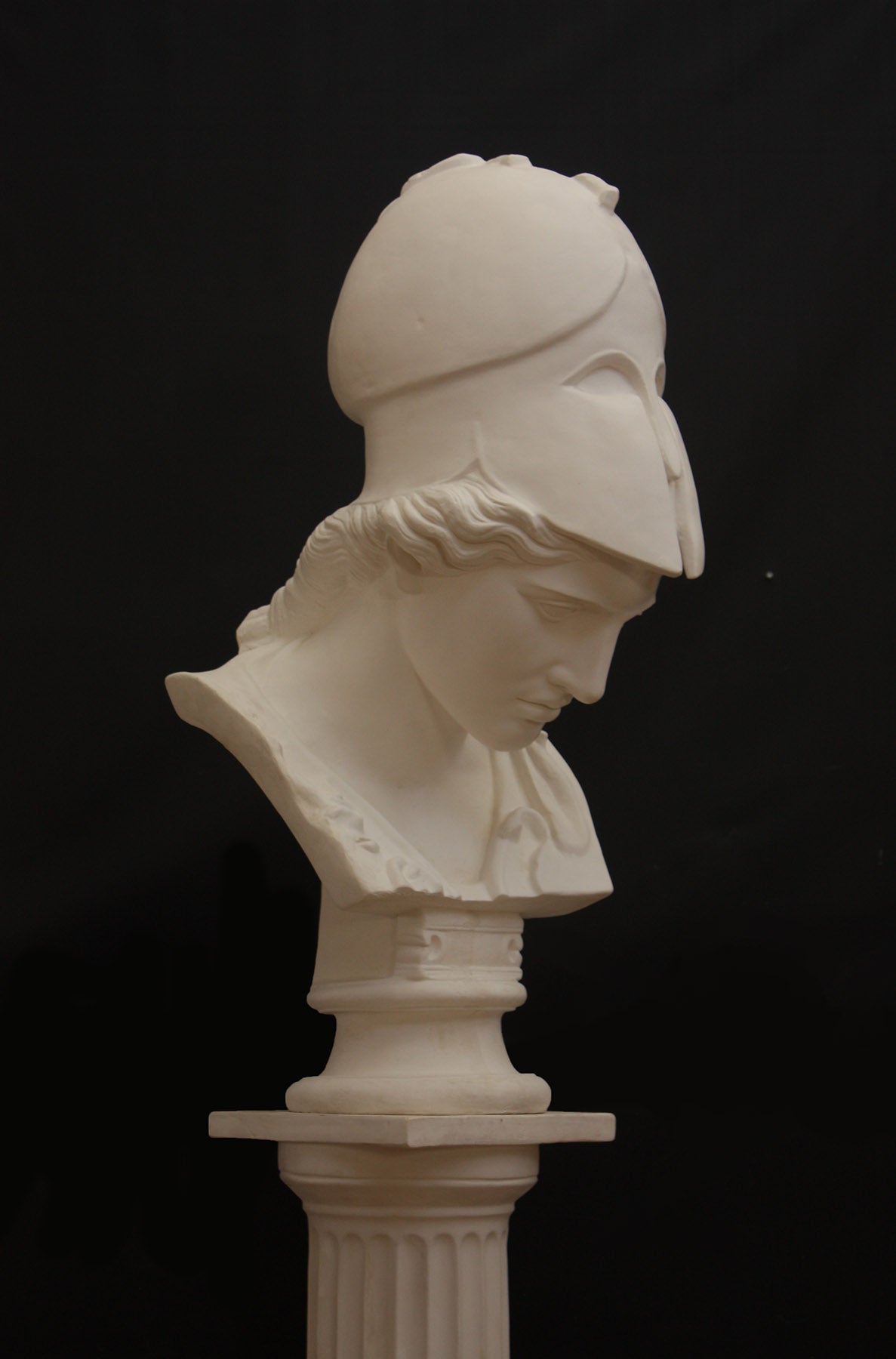 Image of a plaster statue pf a bust of Minerva on a black background