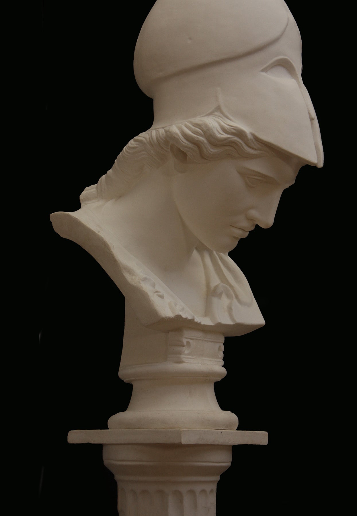 Image of a plaster statue pf a bust of Minerva on a black background