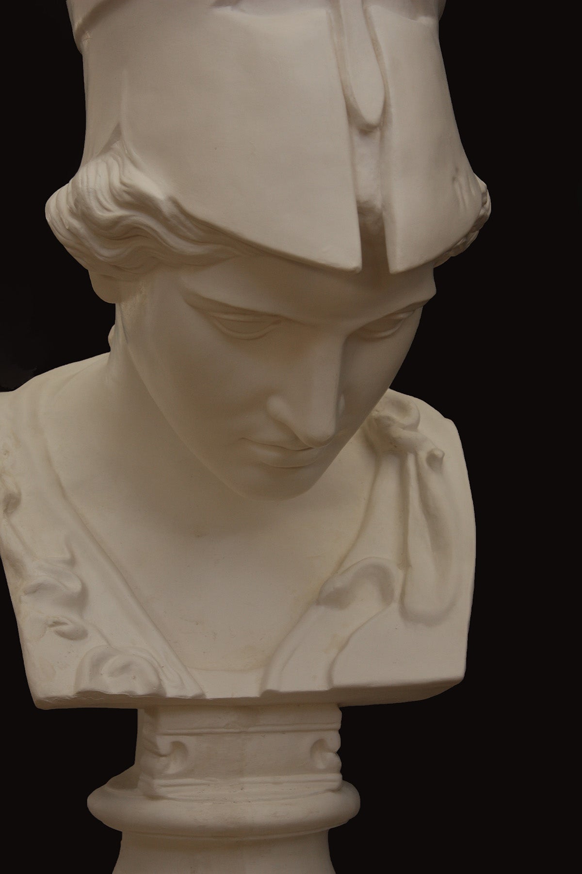 Image of a plaster statue pf a bust of Minerva on a black background