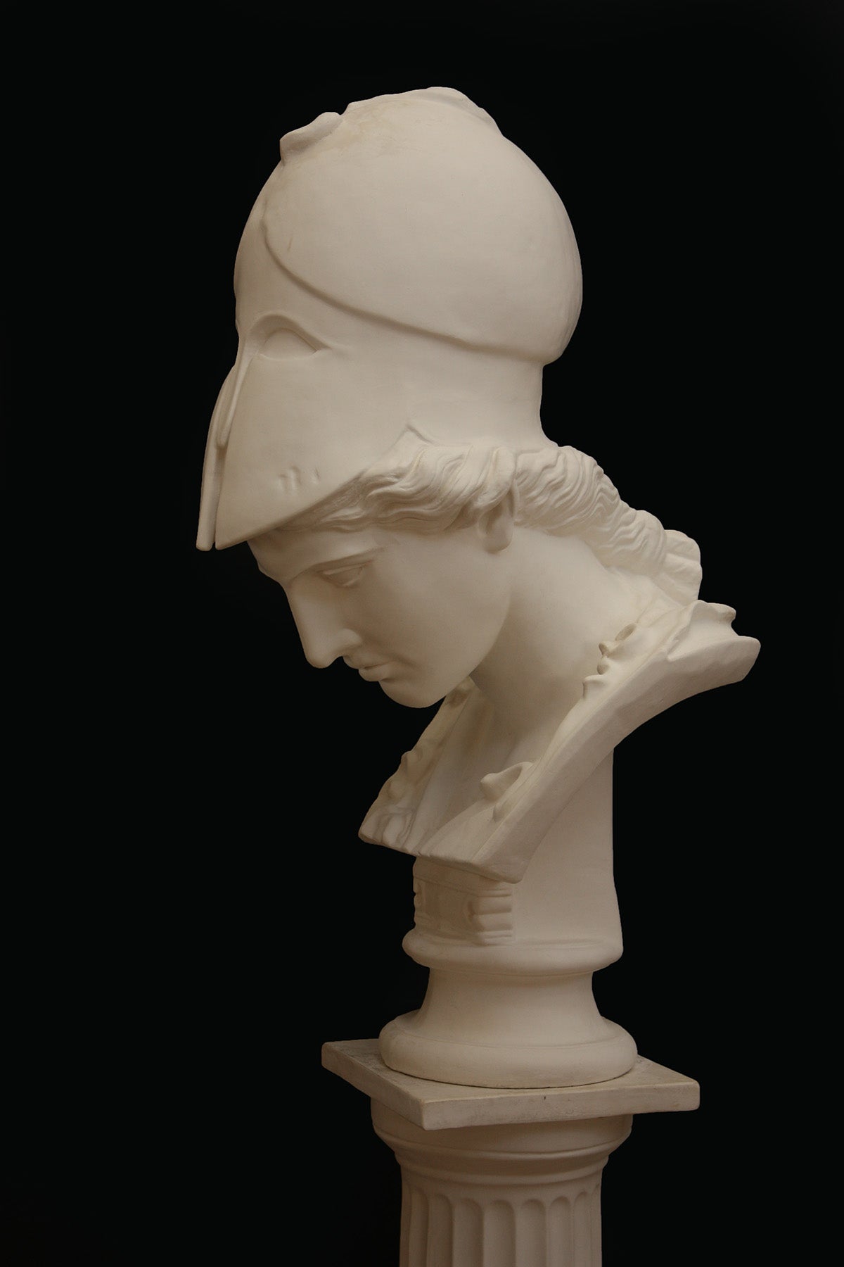 Image of a plaster statue pf a bust of Minerva on a black background