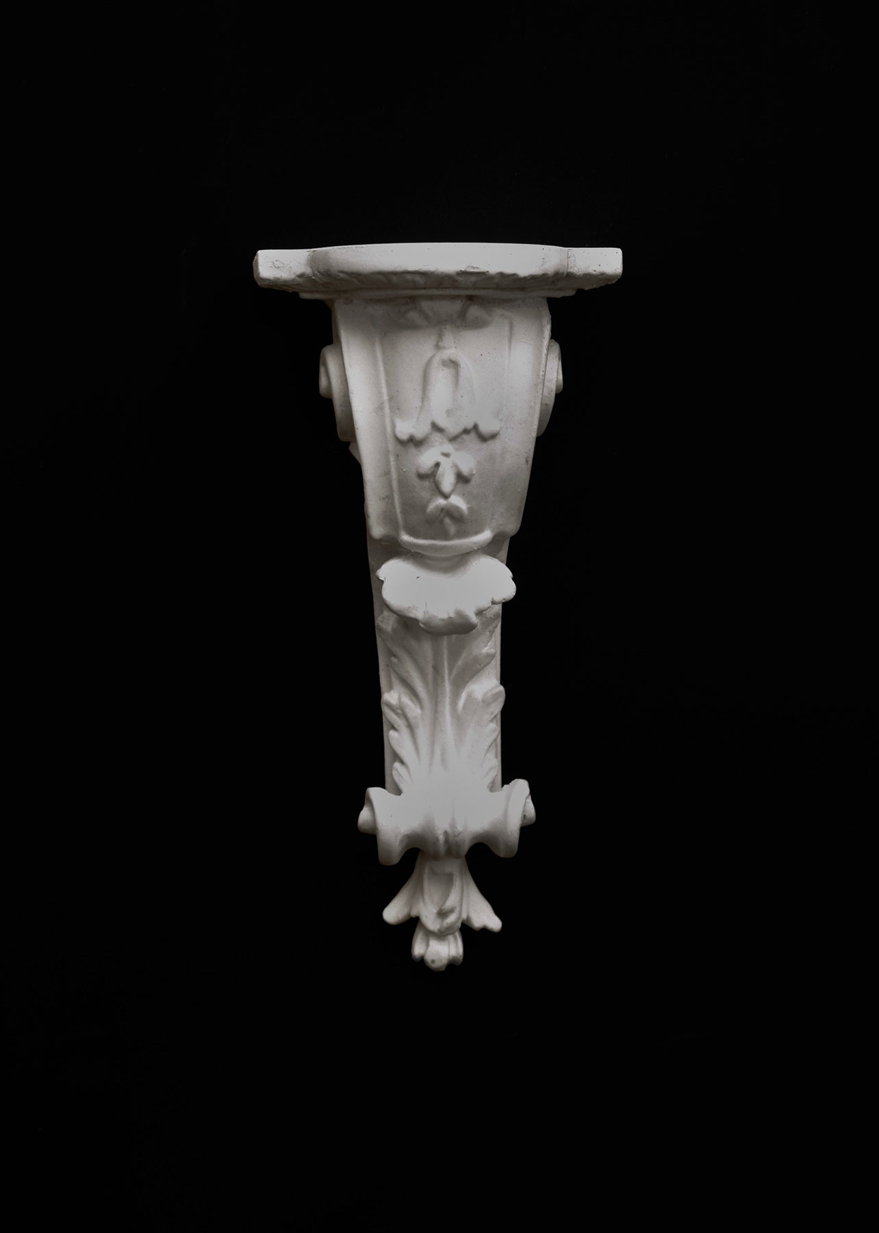 image of a plaster statue of a renaissance bracket on a black background